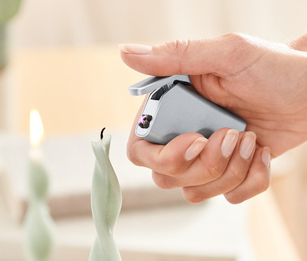 Eine Frau zündet eine Kerze mit einem elektrischen Feuerzeug an.