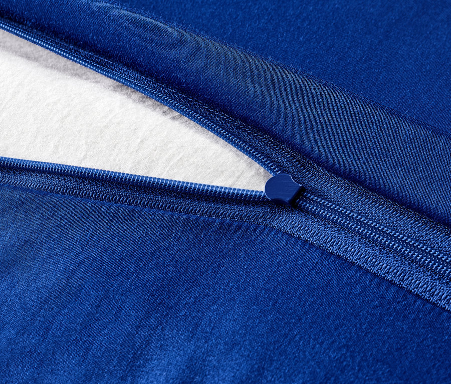 Detailansicht von marineblauer Satin-Bettwäsche mit Reißverschluss und einem Stück weißem Stoff.