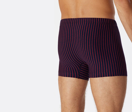 Ein Mann trägt dunkelblaue SCHIESSER Shorts mit roten Streifen aus Bio-Baumwolle, von hinten gesehen.