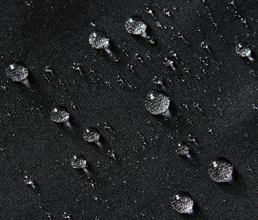 Nahaufnahme einer schwarzen, wasserabweisenden Sporttight mit Wassertropfen auf der Oberfläche.