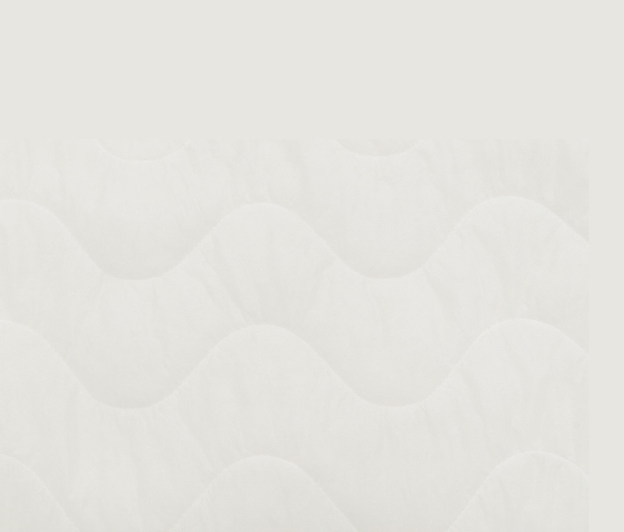 Detailansicht eines weißen Toppers mit wellenförmiger Steppung.