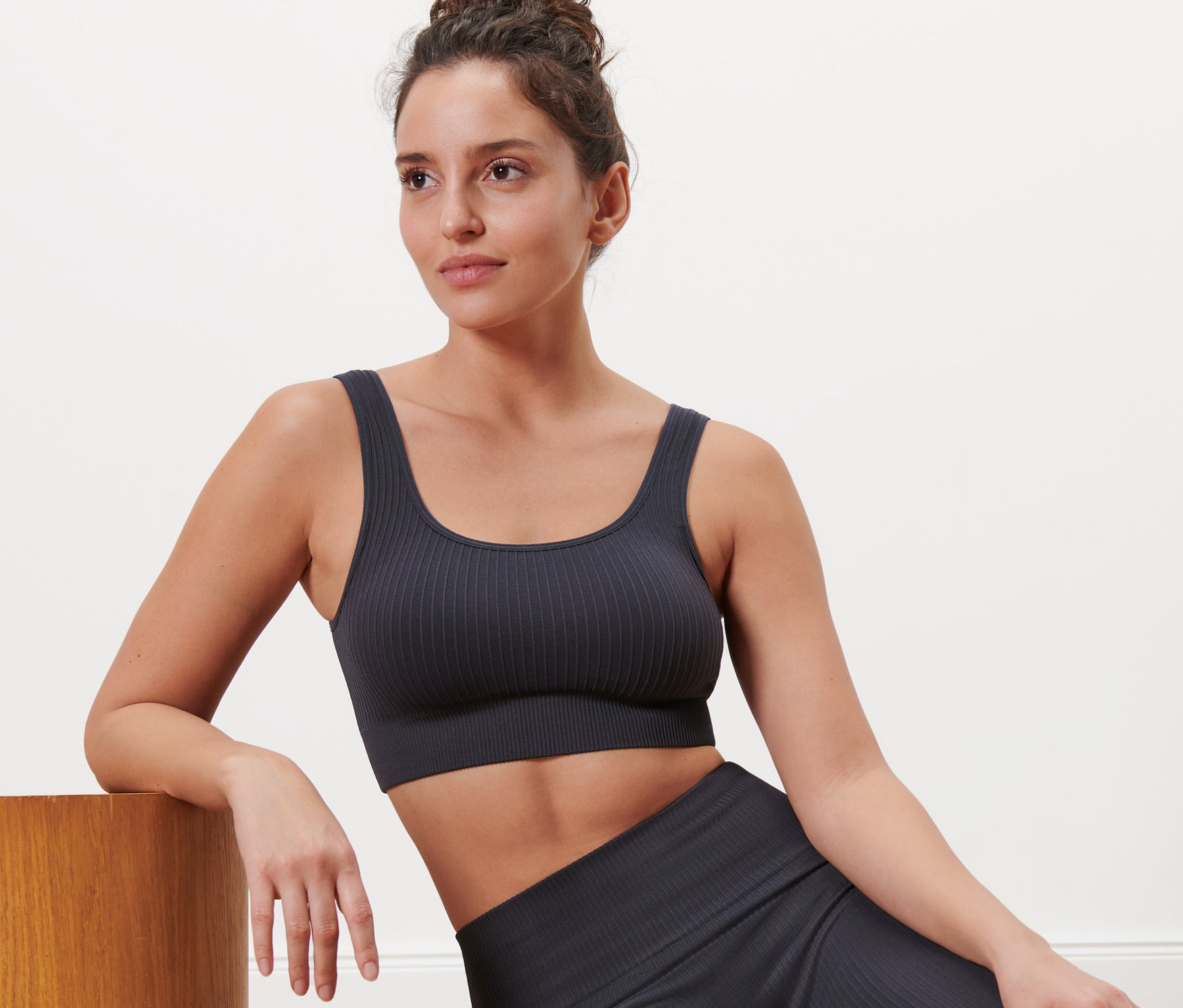 Frau sitzt auf dem Boden und trägt ein anthrazitfarbenes Seamless-Sport-Bustier.