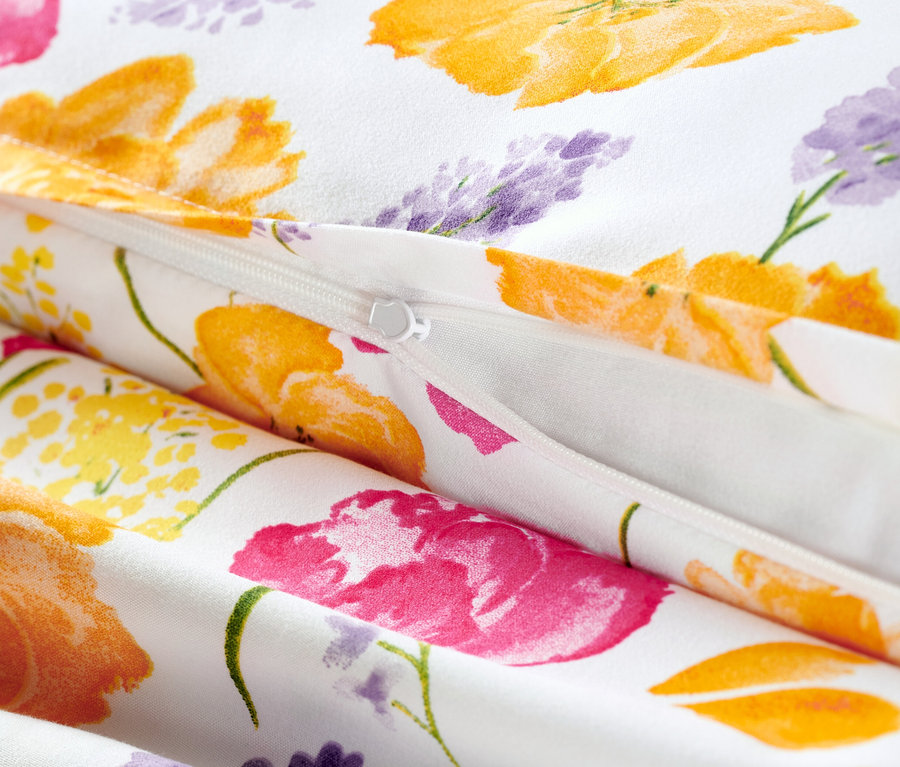 Detailaufnahme von weißer Microfaser-Bettwäsche mit Reißverschluss und Blumenmuster.