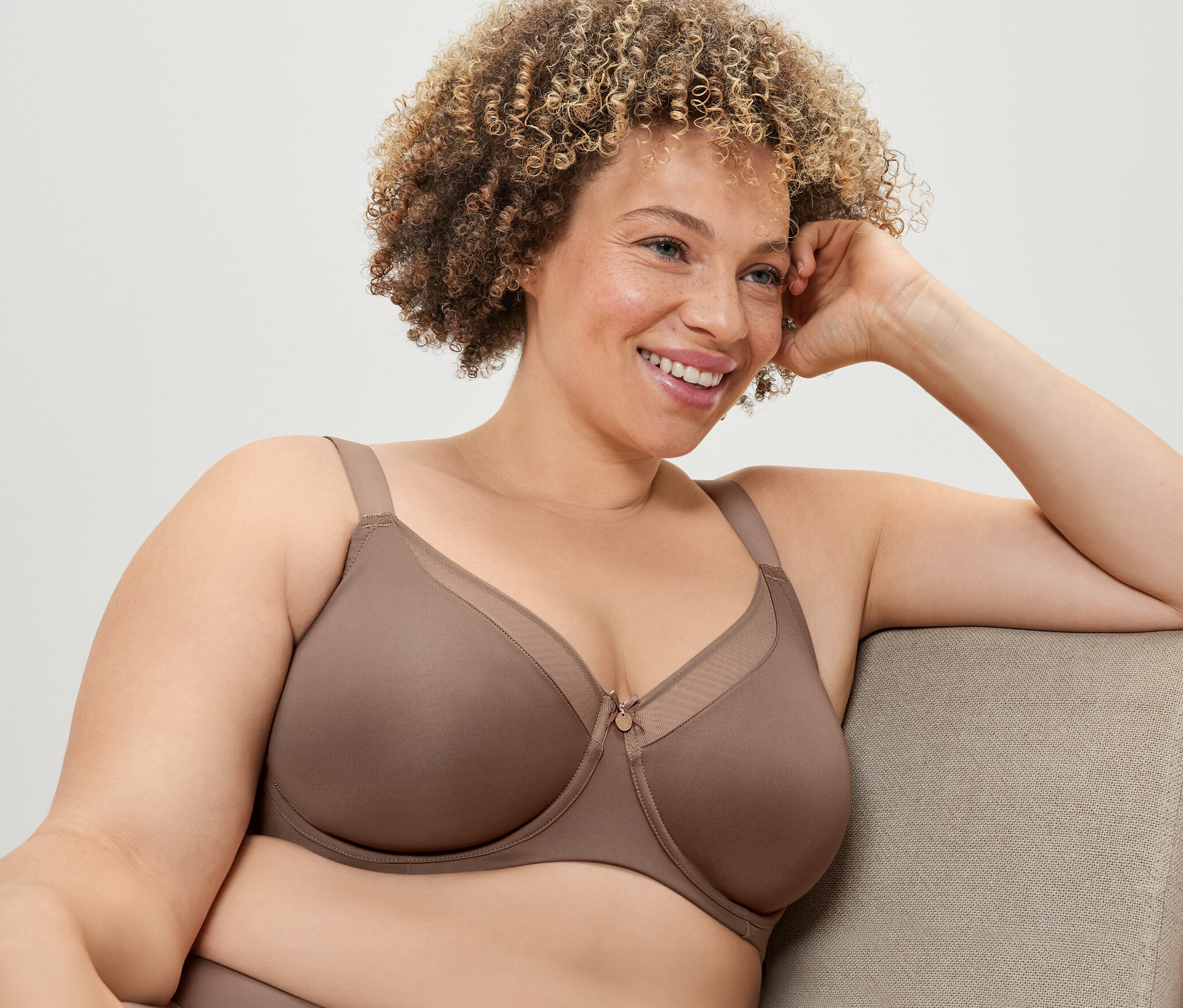 Frau sitzt und trägt einen Minimizer-BH in Nougat.