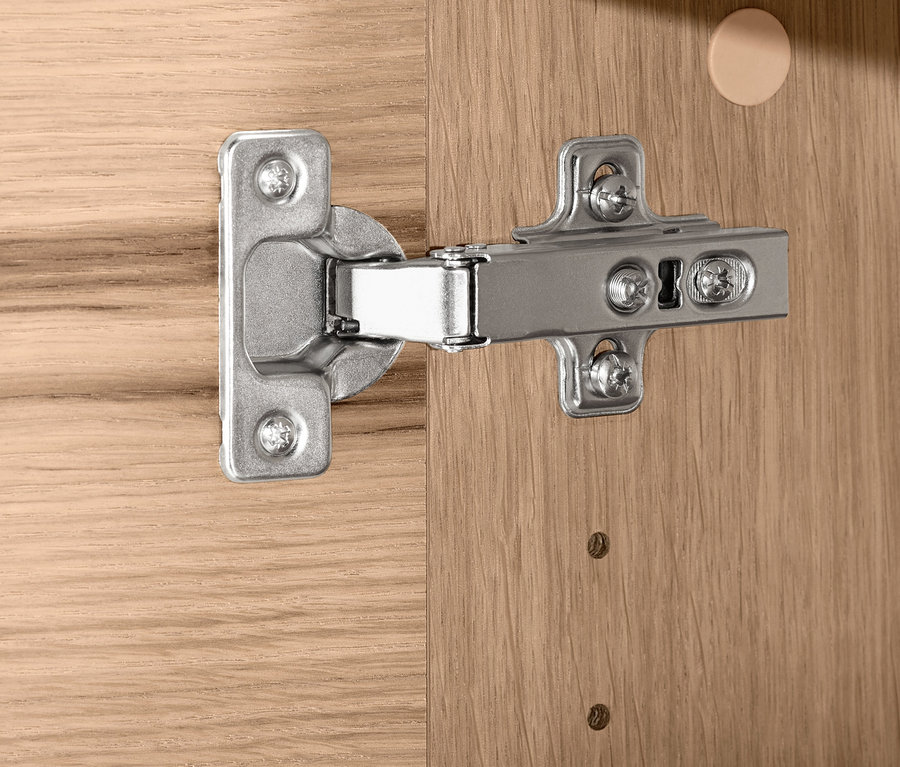 Detail eines silbernen Scharniers an einem Holzmöbelstück.