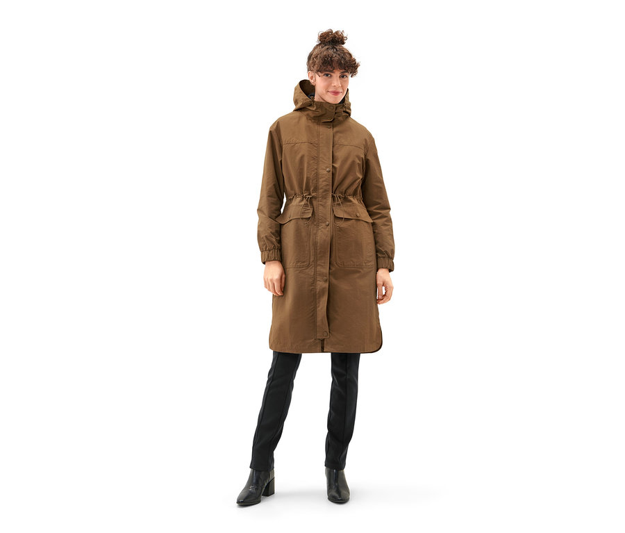 Frau trägt einen braunen Parka mit Weste, schwarze Hosen und Stiefel.