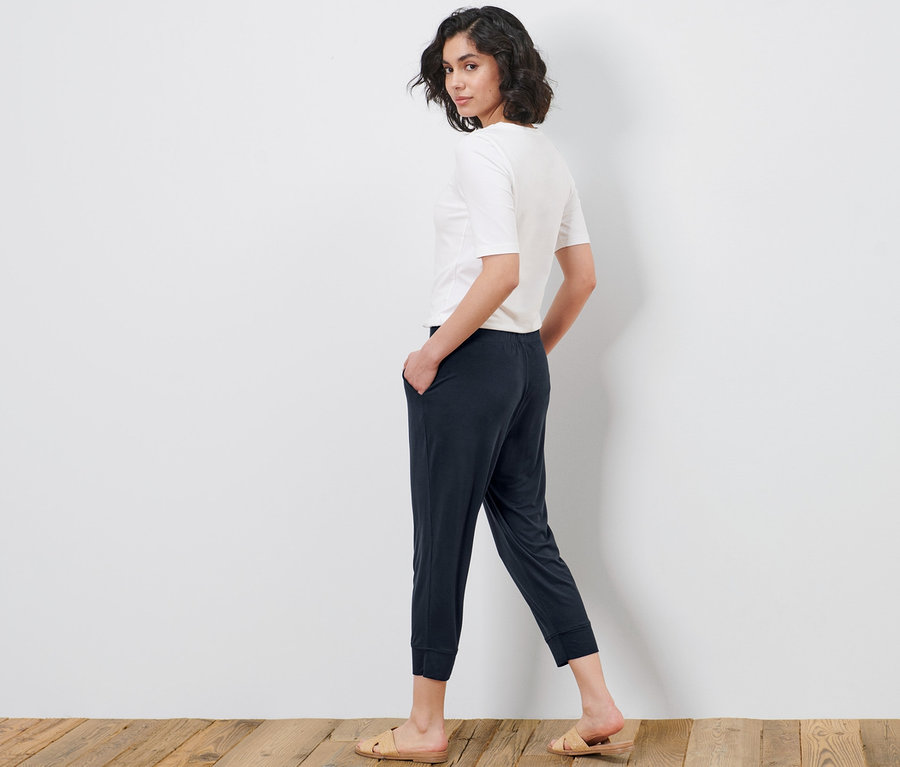 Frau blickt über die Schulter und posiert in einer 3/4-Jerseyhose und einem T-Shirt.