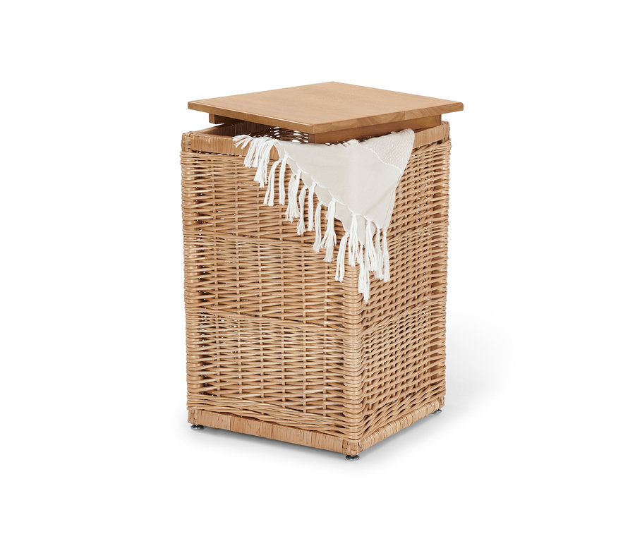 Hohe Truhe aus Geflecht mit Holzdeckel und weißem Tuch mit Fransen.