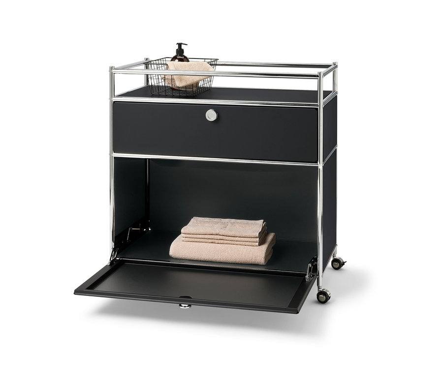 Kommode Metall »CN3« mit einer Schublade, einem Klappfach und Umrandung. Oben Korb mit Handtuch und Spenderflasche. Im unteren Fach liegen gefaltete Handtücher.