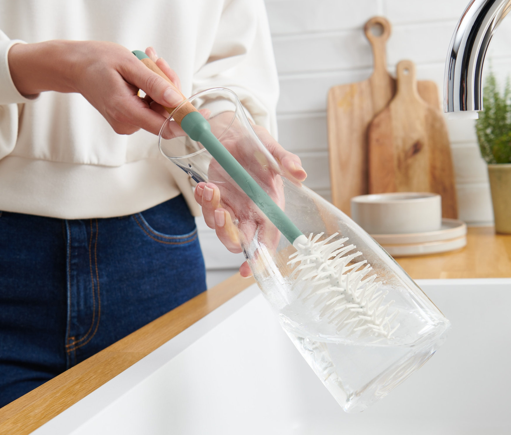 Eine Frau reinigt eine Glasflasche mit einer Gläser-und-Flaschen-Spülbürste.