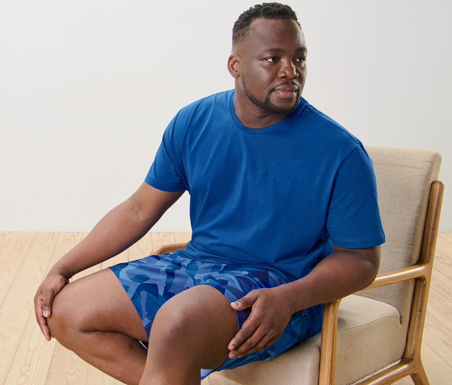 Mann sitzt auf einem Stuhl und trägt einen Shorty-Pyjama.