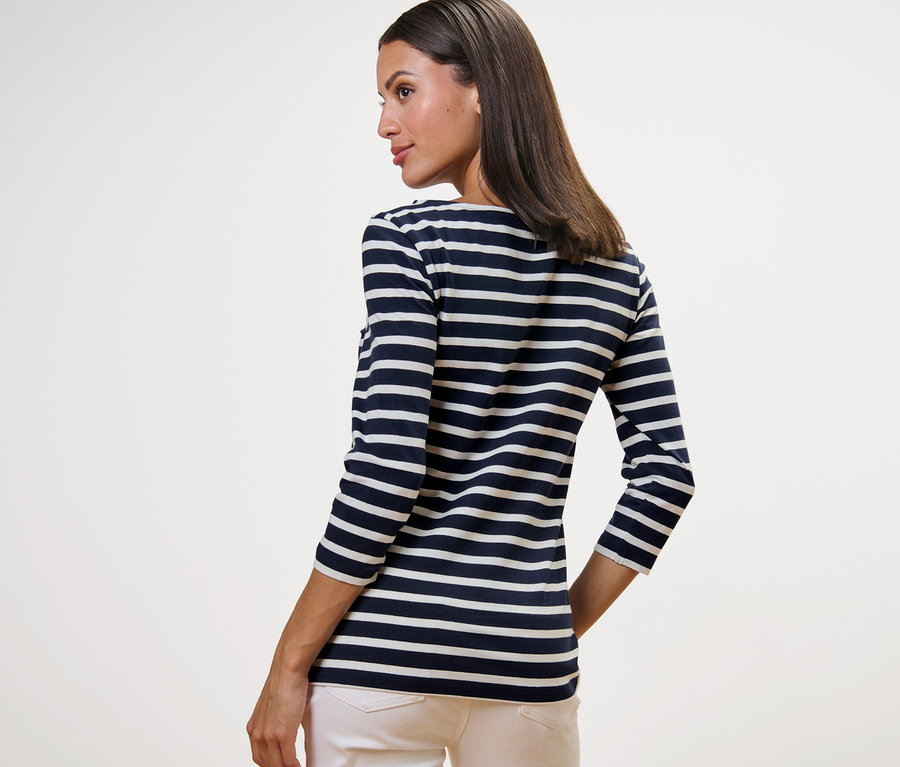 Frau trägt ein gestreiftes Shirt mit 3/4-Arm, navy gestreift, und eine helle Hose.