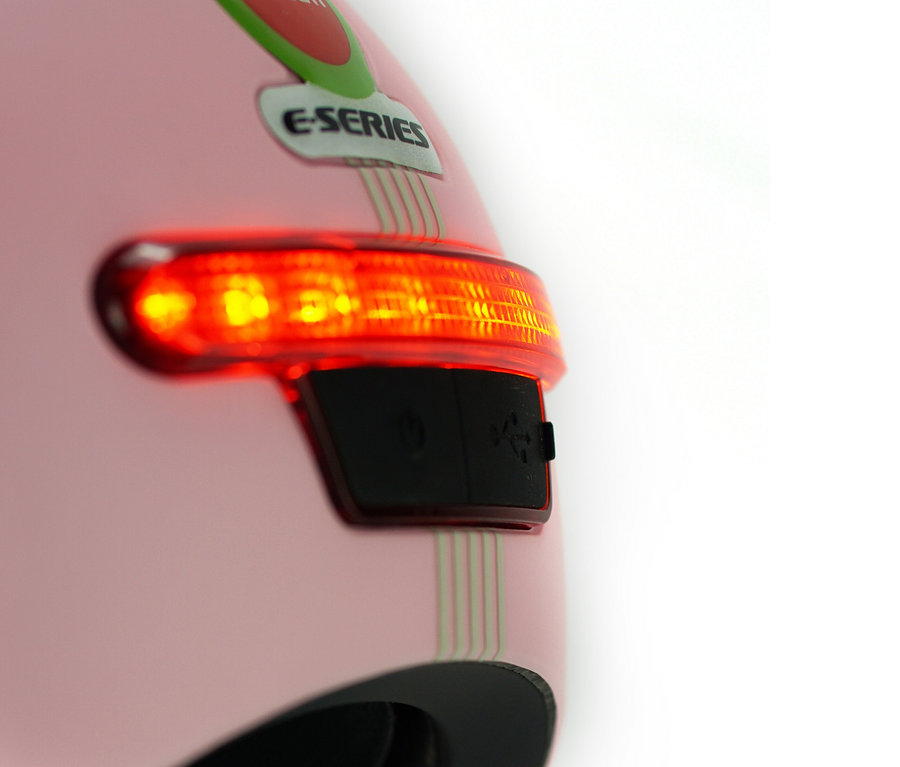 Detailaufnahme eines rosa Melon E-Series Fahrradhelms »Lotus« mit eingeschaltetem Rücklicht.