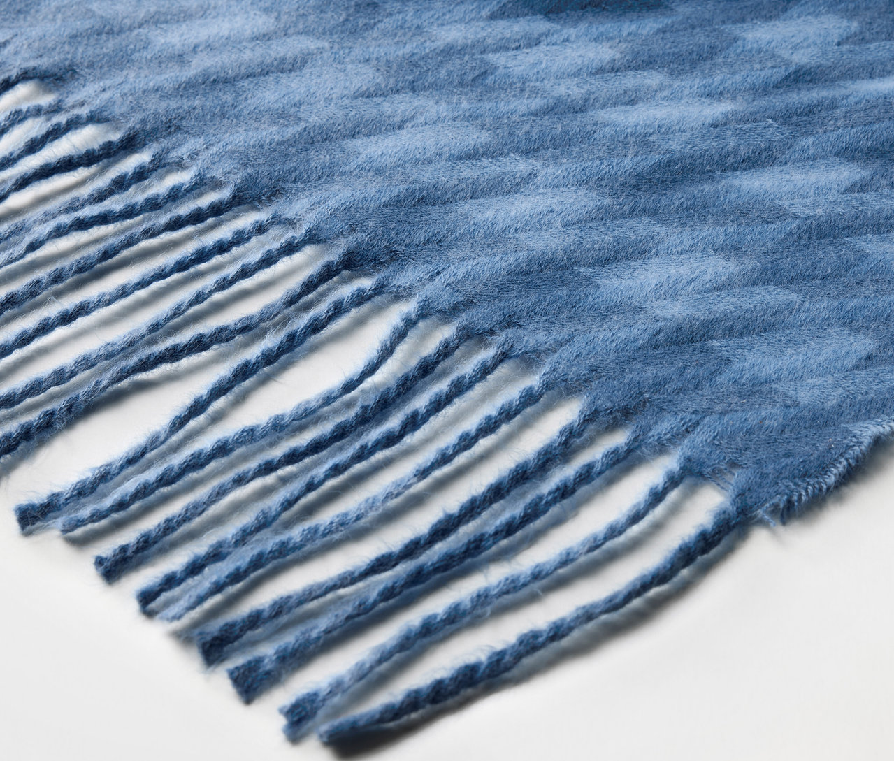 Detailaufnahme eines blauen Schals mit Fransen.