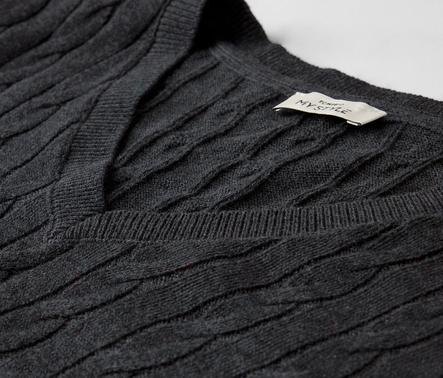Detailaufnahme eines grauen Zopfmusterpullovers mit V-Ausschnitt.