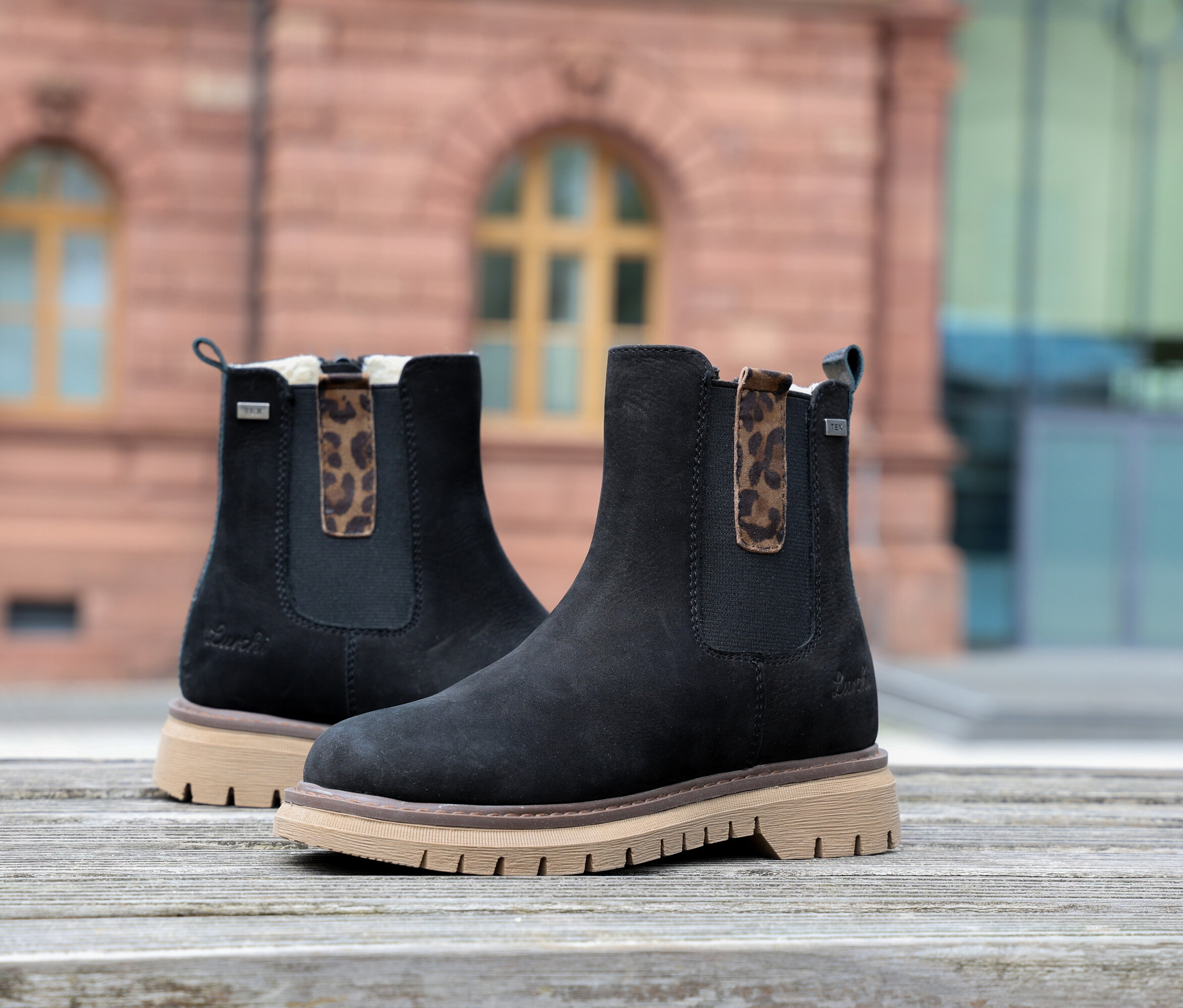 Zwei schwarze LURCHI »Elena-TEX« Stiefel auf einer Holzoberfläche.