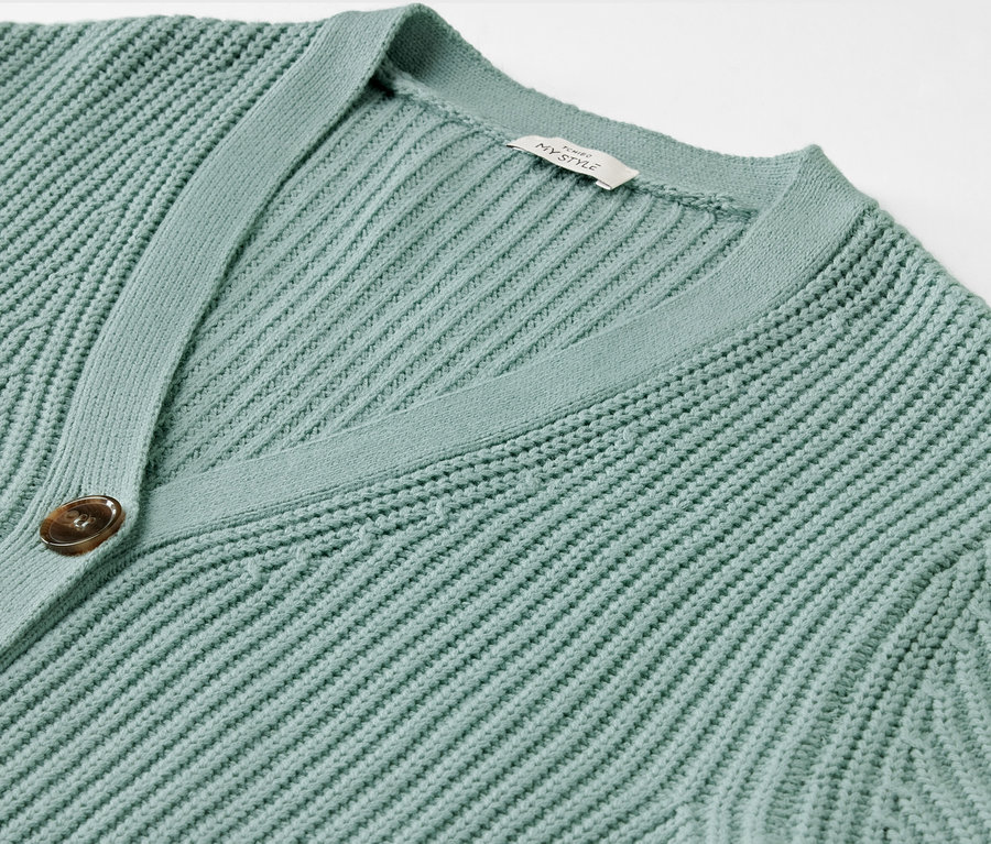 Detailansicht eines salbeigrünen Grobstrick-Cardigans.