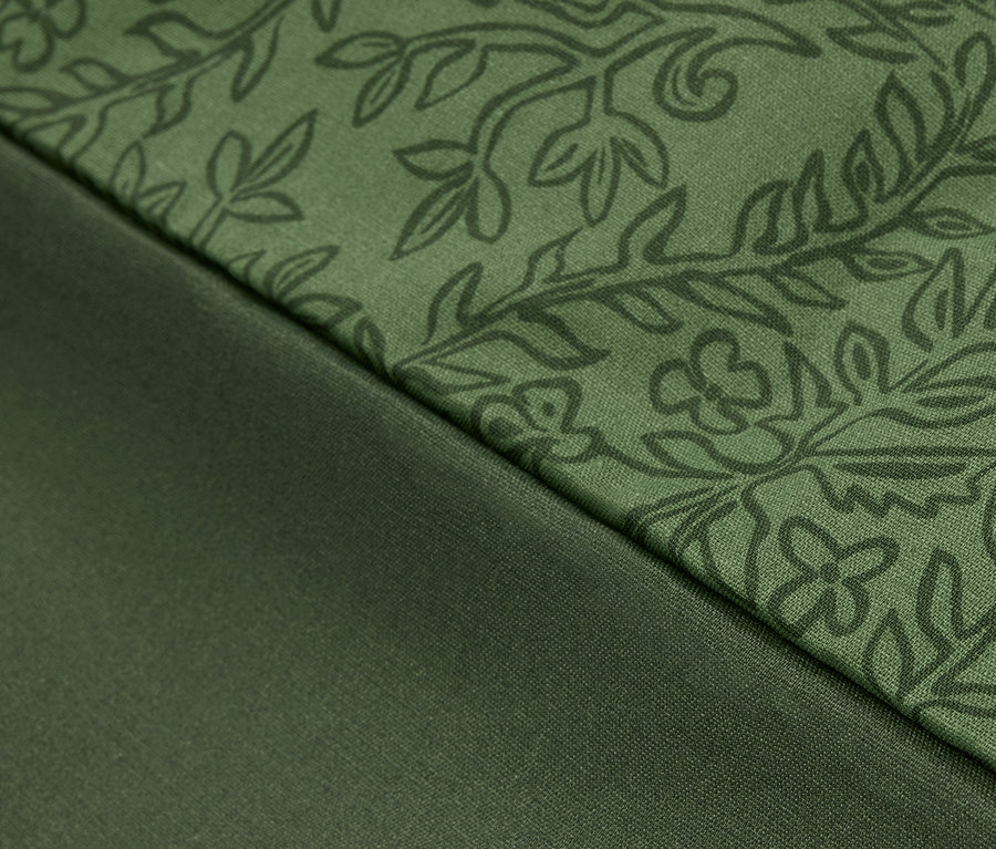 Detailaufnahme eines grünen Stoffes mit Blumenmuster und eines glatten grünen Stoffes.