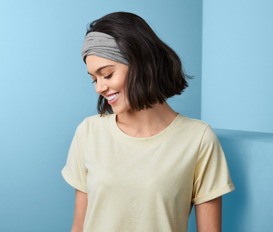 Lächelnde Frau mit Multifunktionstuch im Haar.