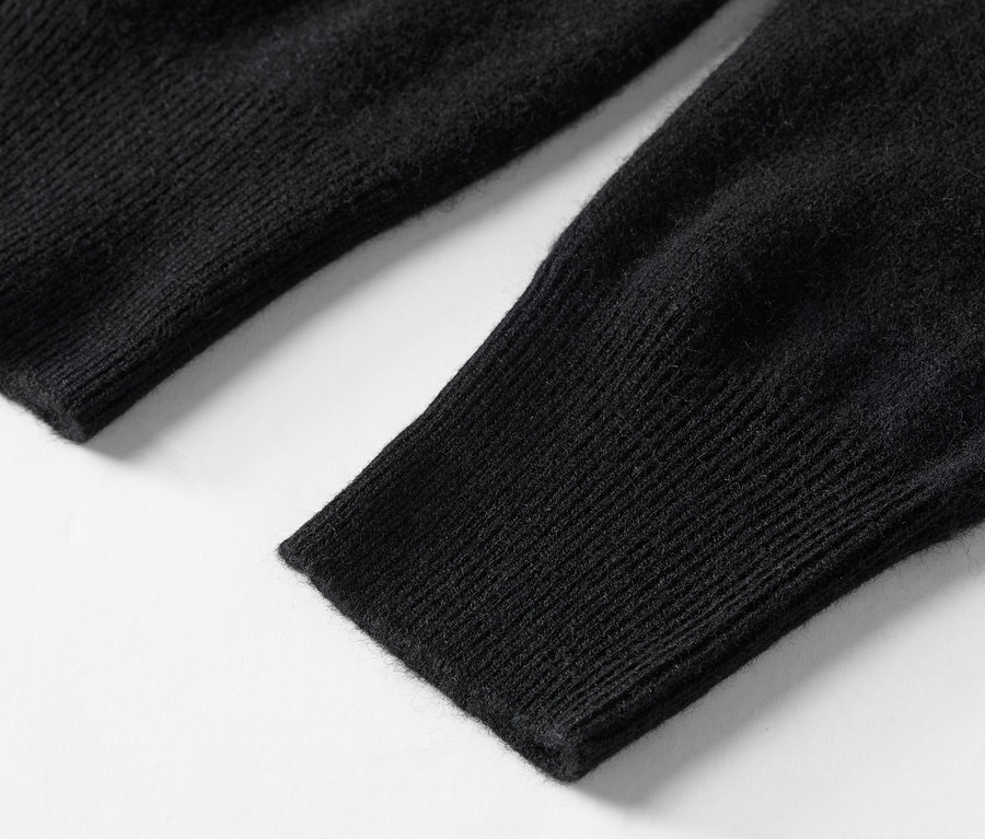 Detailaufnahme eines schwarzen Strickärmels eines Pullovers.