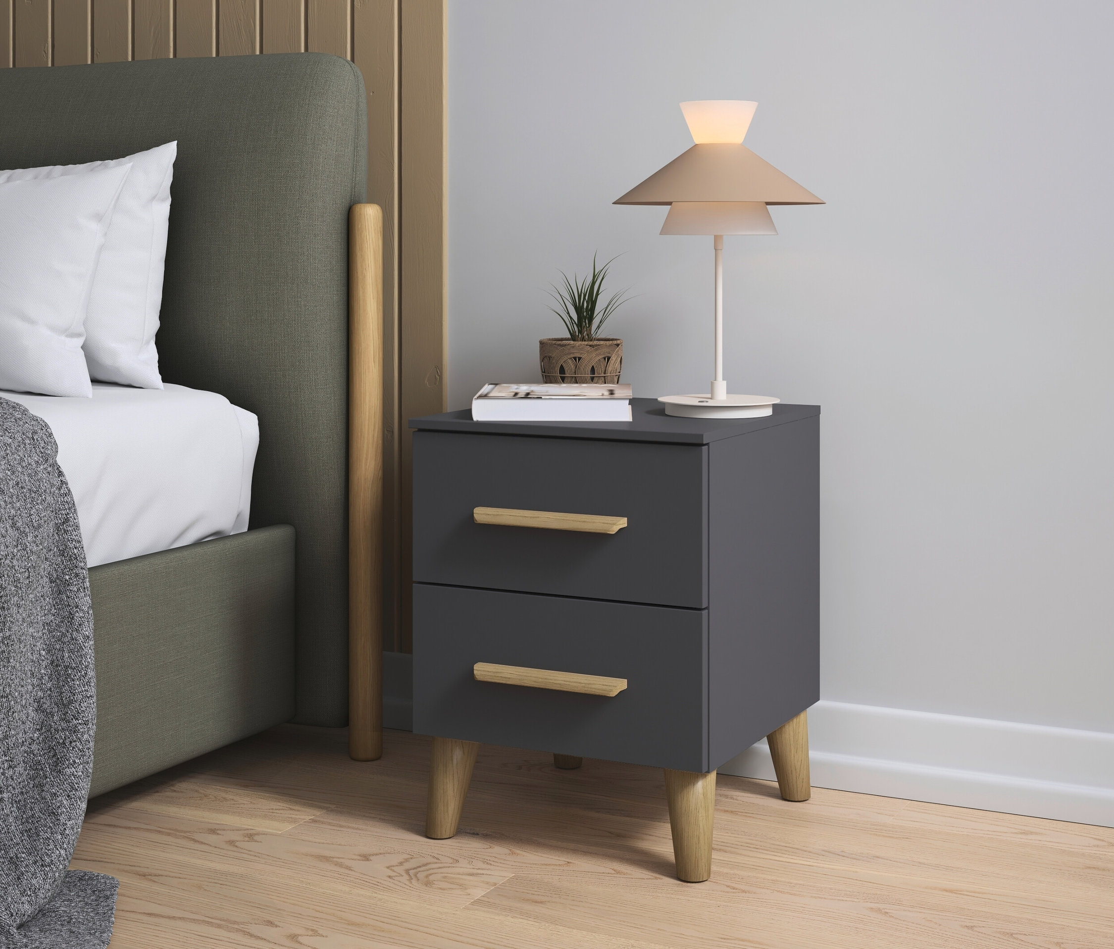 Ein grauer Nachttisch mit zwei Schubladen steht neben einem Bett mit olivgrünem Kopfteil und weißen Kissen.