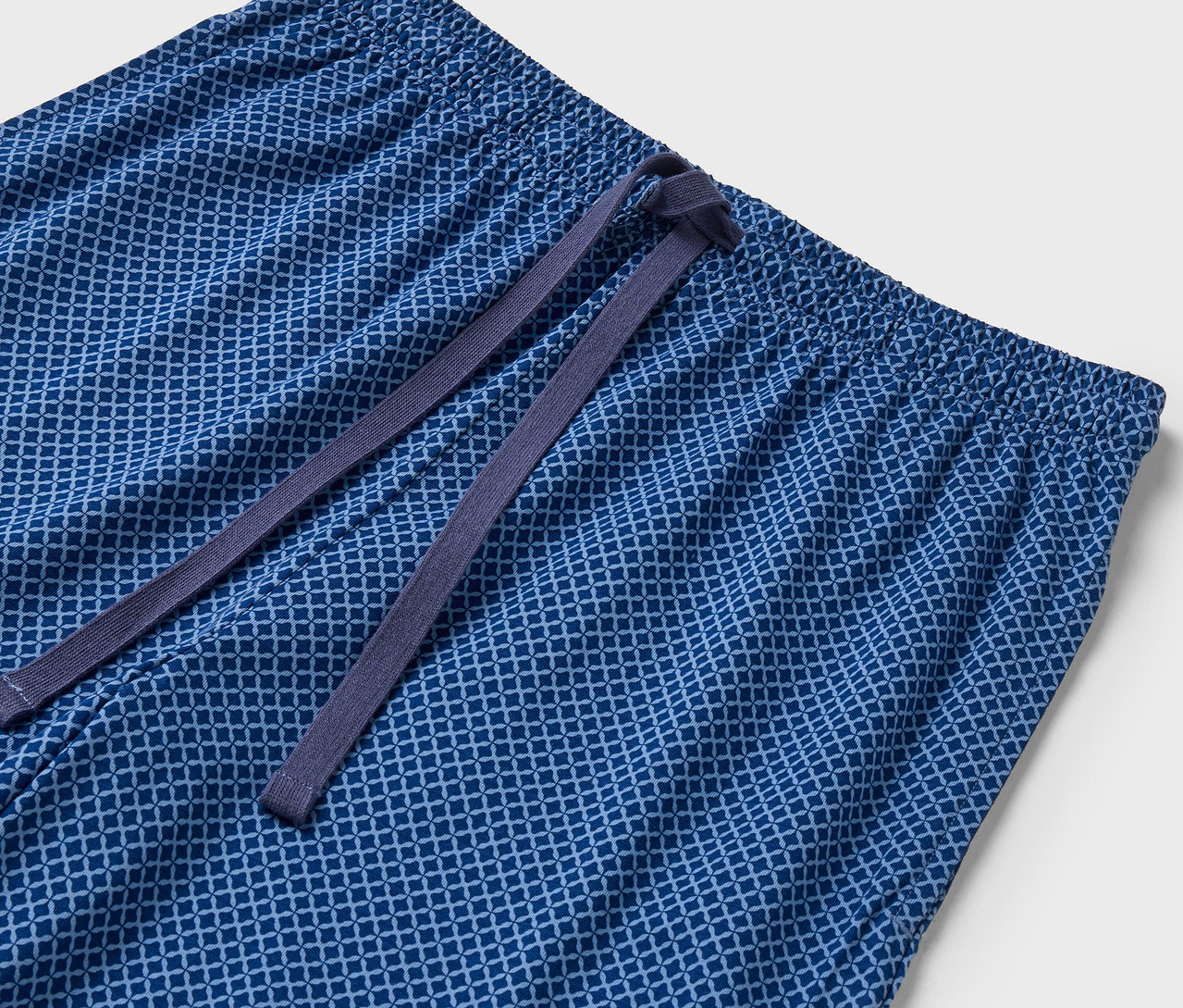 Detailaufnahme einer blauen, gemusterten Hose mit elastischem Bund und Kordelzug.
