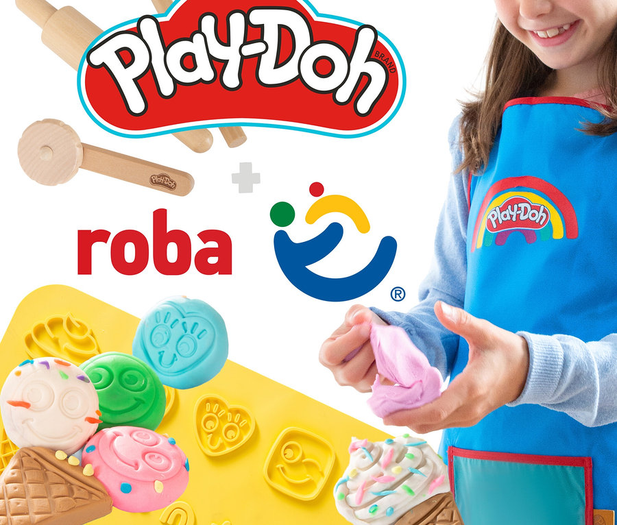 Ein Kind spielt mit rosa Play-Doh vor einer gelben Formmatte mit verschiedenen Formen und einem blauen Play-Doh-Lätzchen.