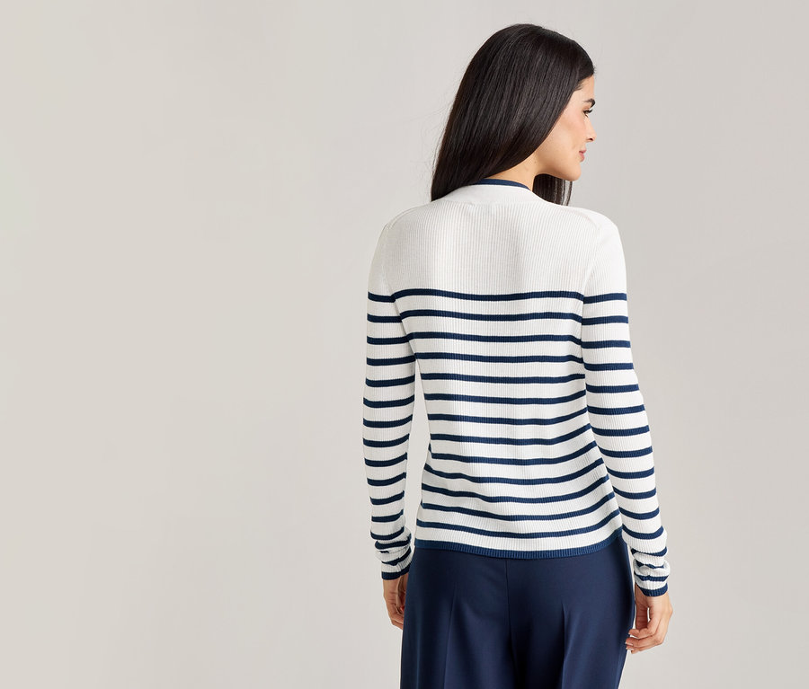 Eine Frau von hinten, mit dunklen Haaren, trägt einen weiß-blau gestreiften Pullover und eine dunkelblaue Hose.