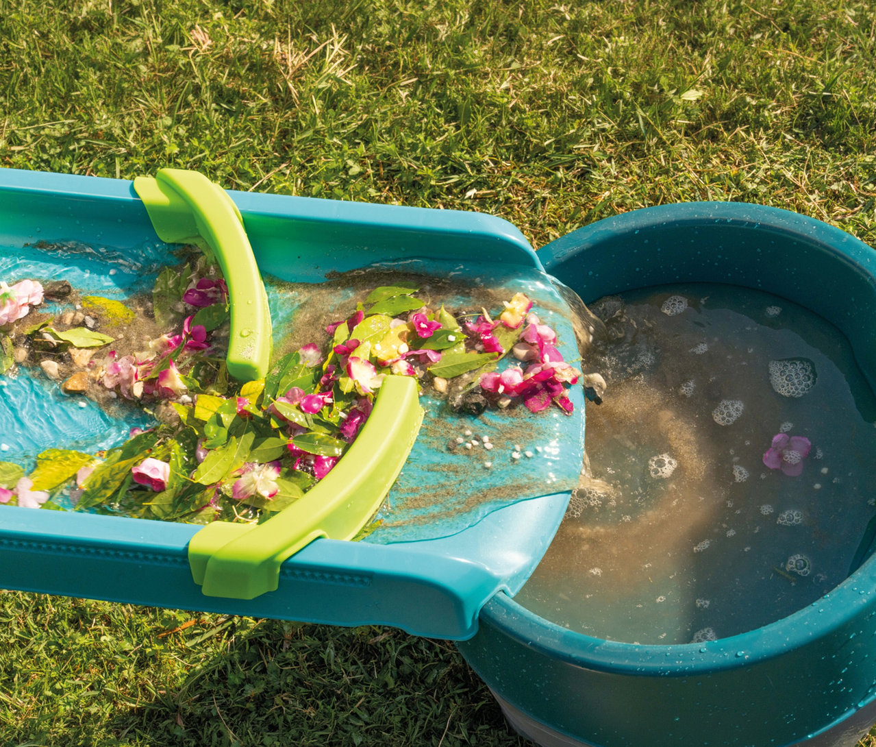 Wasser mit Blättern fließt von der AquaPlay »Mudway STREAM« Matschbahn in einen Eimer.