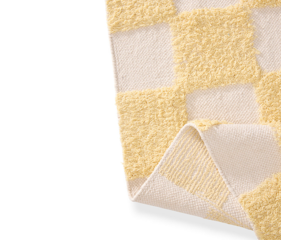 Nahaufnahme eines Schachbrettmusters mit abwechselnd gelben Zotteln und cremefarbenem Stoff.