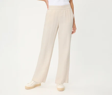 Person trägt hellbeige Olsen Leinenhose mit weitem Bein und Gummibund, dazu weiße Espadrille-Sneaker.