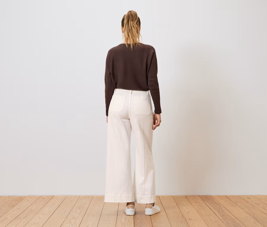 Frau von hinten, trägt ein dunkelbraunes Oberteil und eine weiße Wide Leg Jeans ‒ Fit »Viki«.
