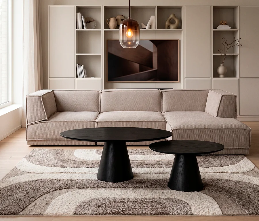 Modernes Wohnzimmer mit beigem Ecksofa, davor zwei schwarze WOOOD Couchtische »Posture« (Ø ca. 120 cm und Ø ca. 70 cm) auf einem gemusterten Teppich. Im Hintergrund eine Regalwand mit TV.