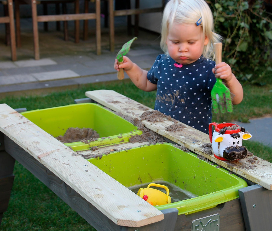 Kleinkind spielt am EXIT Spieltisch mit Bank »Aksent« mit Sand.