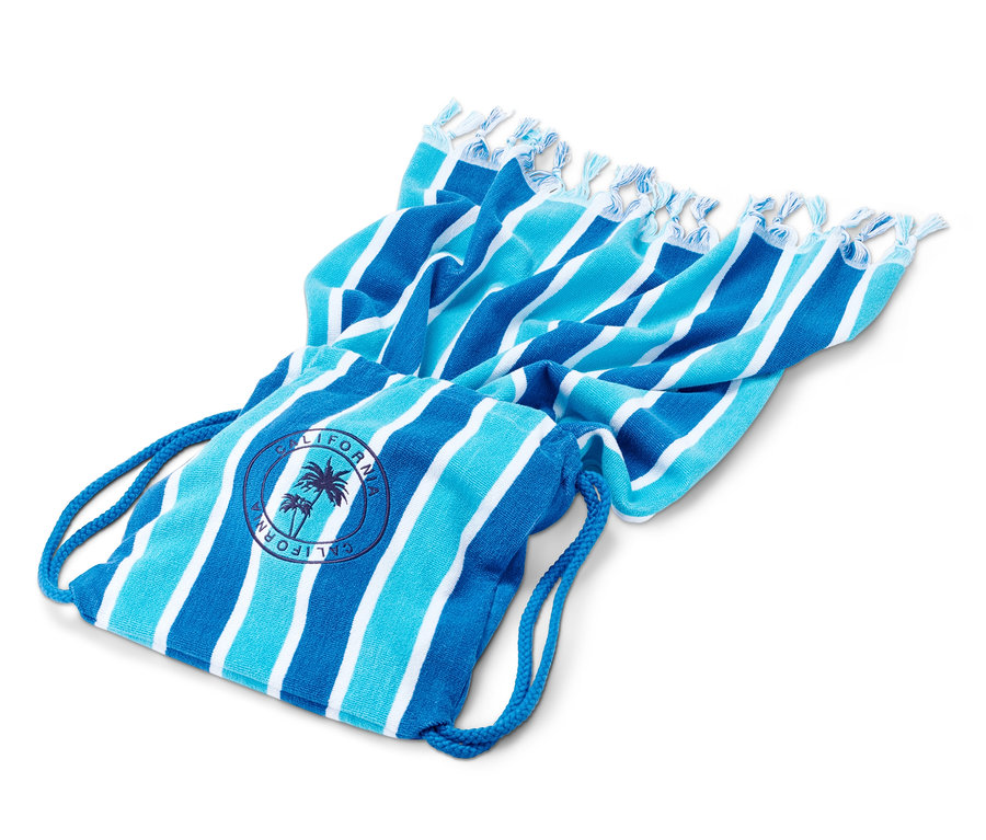 Gestreiftes Strandtuch mit Fransen liegt auf einer blau-weissen Tasche.