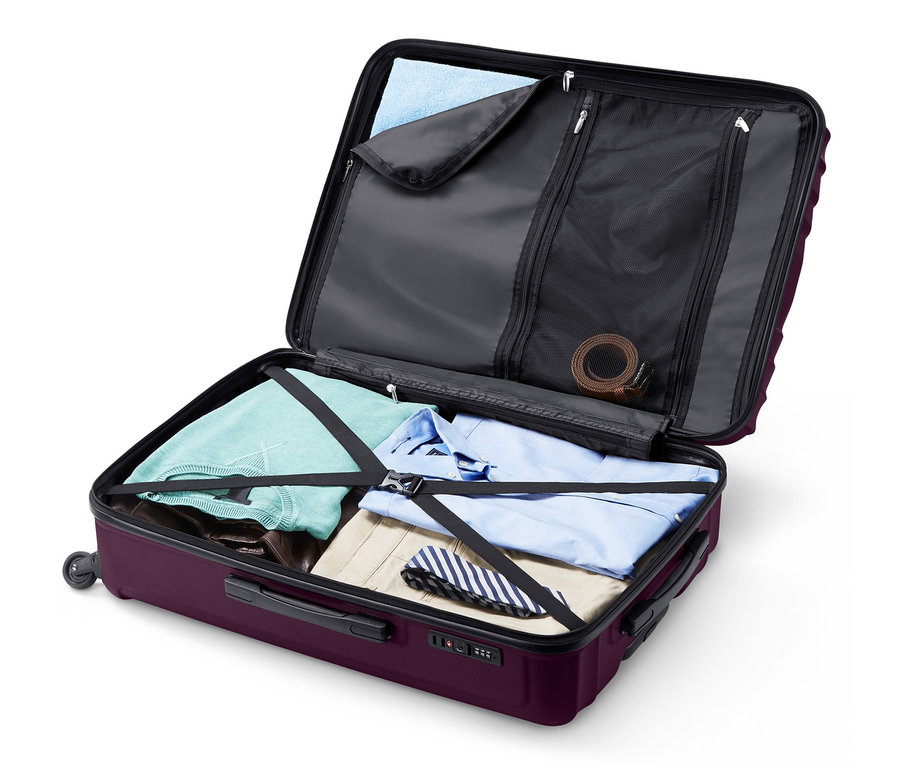 Geöffneter, großer Hartschalen-Koffer in Lila Farbe, gefüllt mit Kleidung.