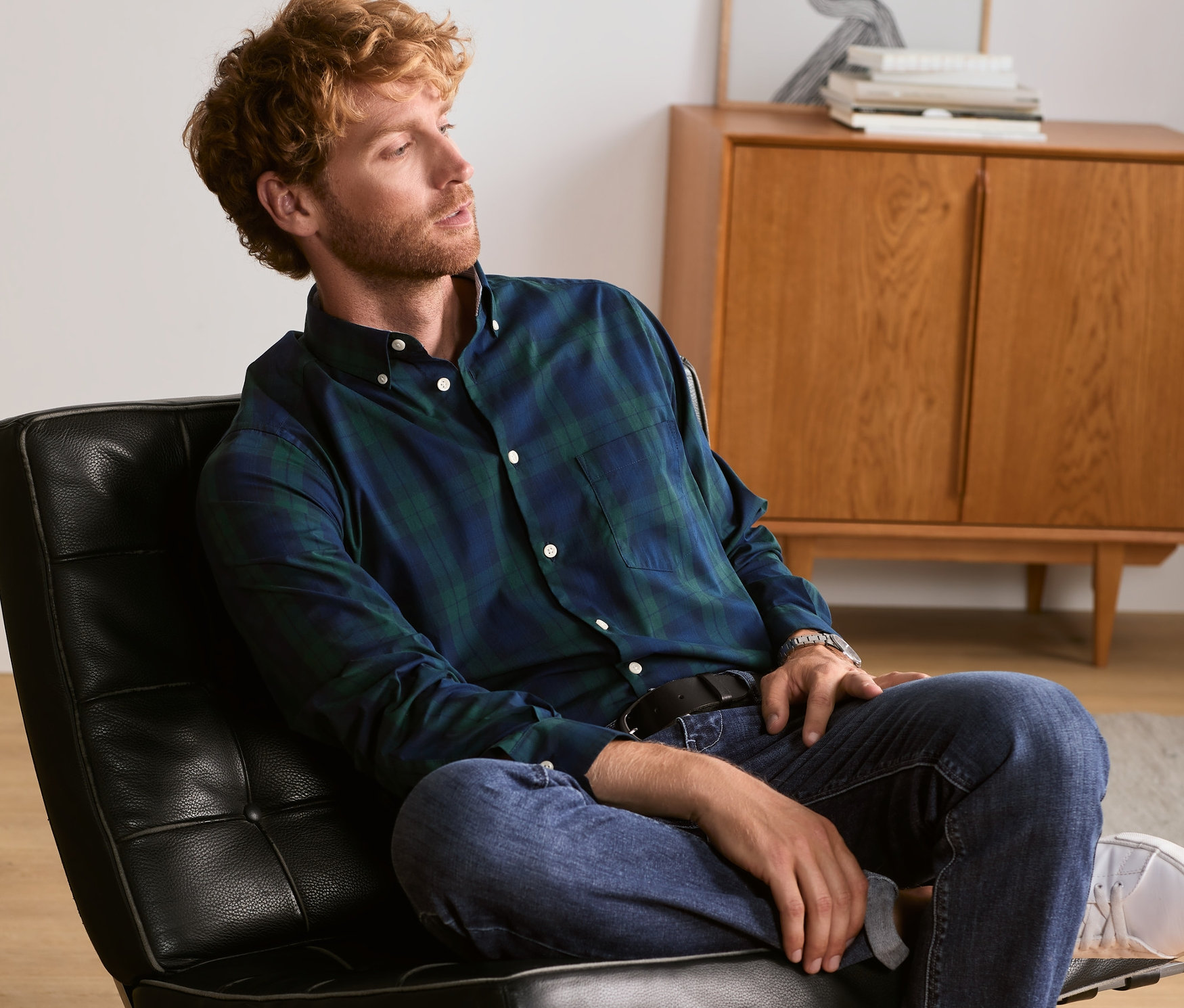 Mann sitzt auf einem Sessel und trägt ein Hemd.