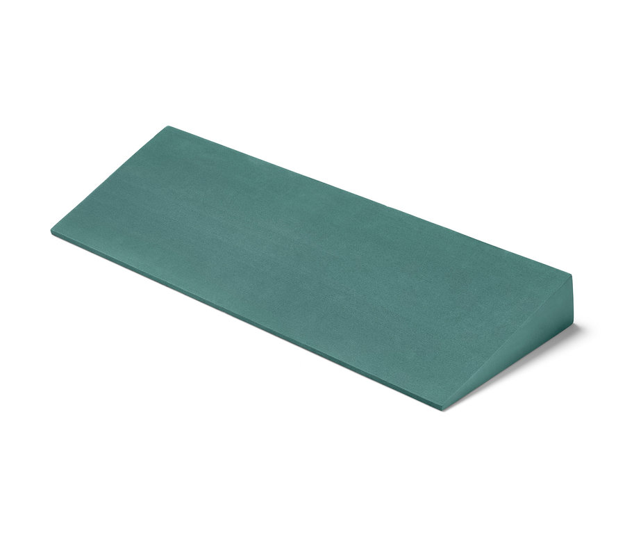 Ein grüner Yoga-Wedge liegt auf einem weißen Hintergrund.