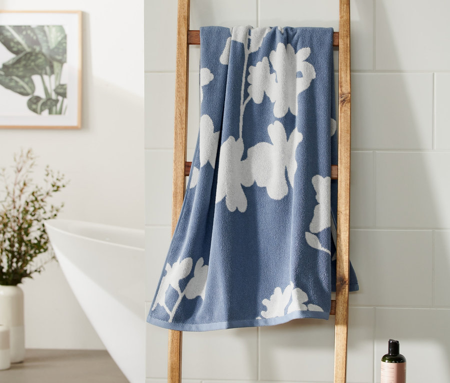 Blaues Jacquard-Badetuch hängt auf einer Holzleiter im Badezimmer.