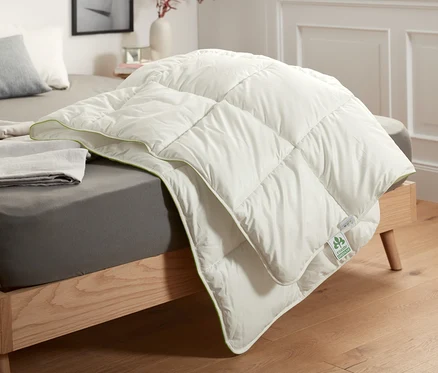 Auf einem Bett liegt ein irisette® greenline Steppbett mit Faserfüllung.