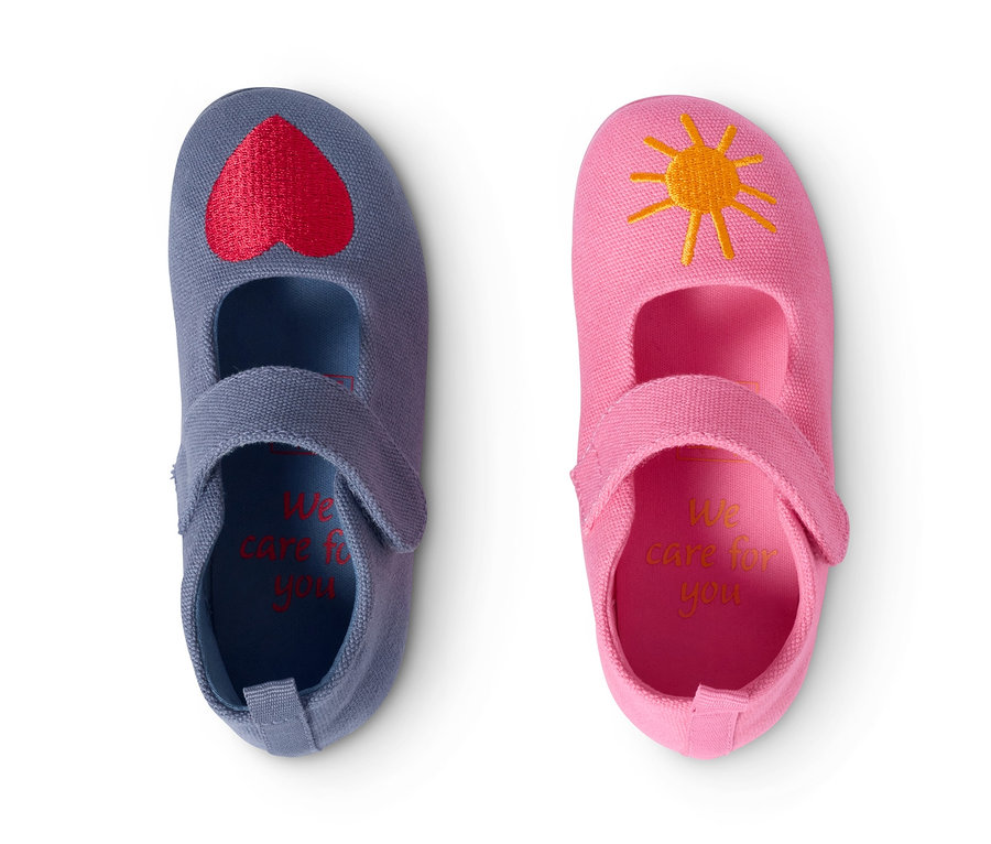 Zwei Paar Hausschuhe aus recyceltem Material: ein Paar blau mit rotem Herz, ein Paar rosa mit gelber Sonne.