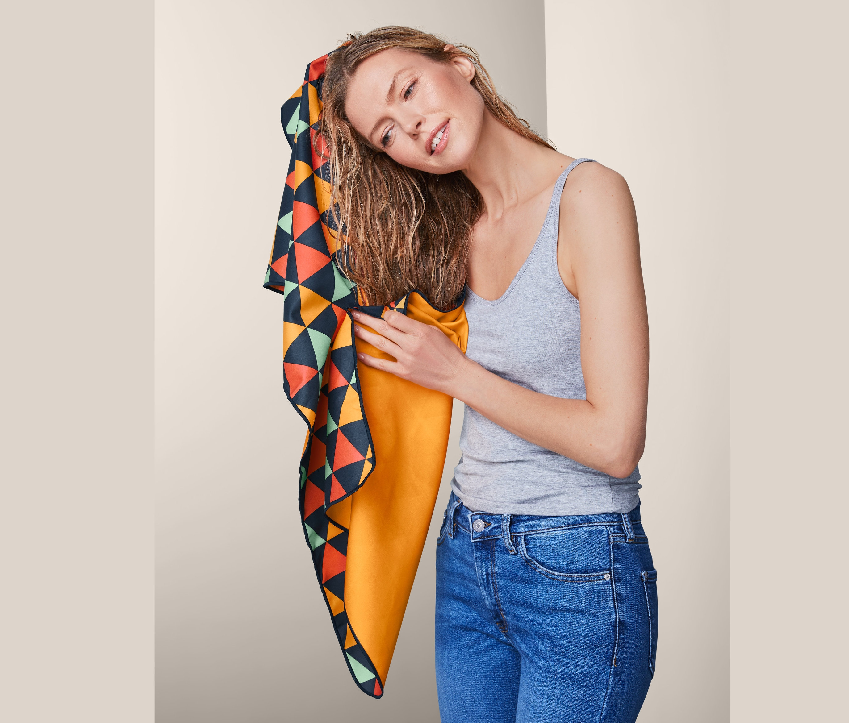 Frau trocknet ihre Haare mit einem mehrfarbigen Outdoor-Handtuch, ca. 50 x 100 cm.