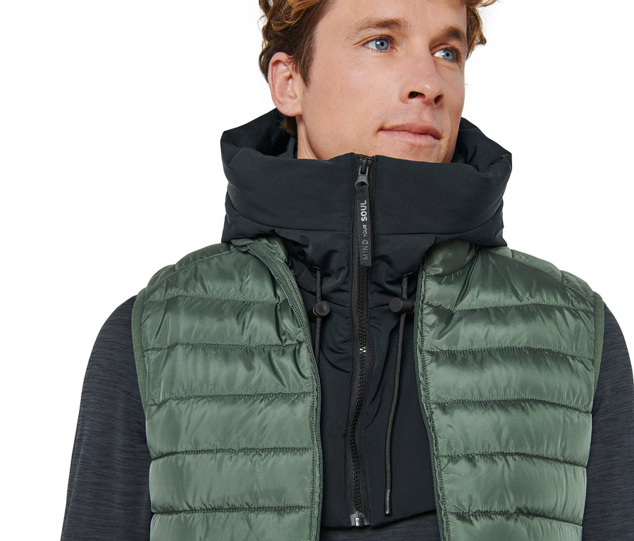 Mann trägt grüne Weste und wattierte Kapuze mit Stehkragen.