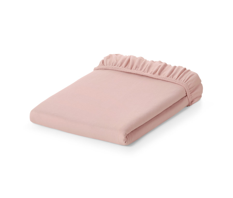 Ein rosafarbenes Jersey-Spannbettlaken gefaltet auf einem weißen Hintergrund.