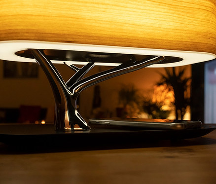 Tischleuchte mit induktiver Ladestation, BT-Lautsprecher und Lampe, sowie ein Telefon.