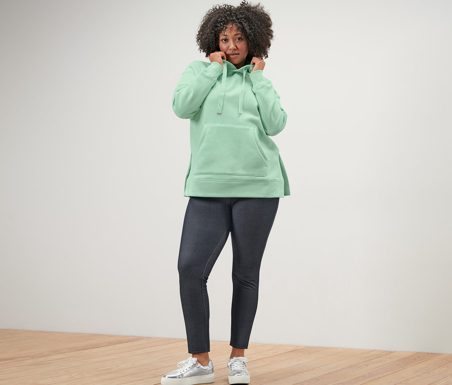 Frau trägt langes Kapuzensweatshirt und Leggings in Jeansoptik.