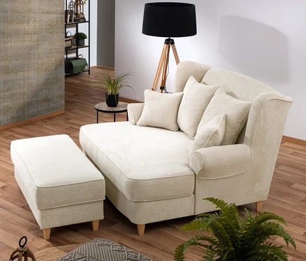 Wohnzimmer mit einer beige aufklappbaren Hockerbank mit Stauraum und einem XXL-Ohrensessel »Harvard« aus Cordstoff.