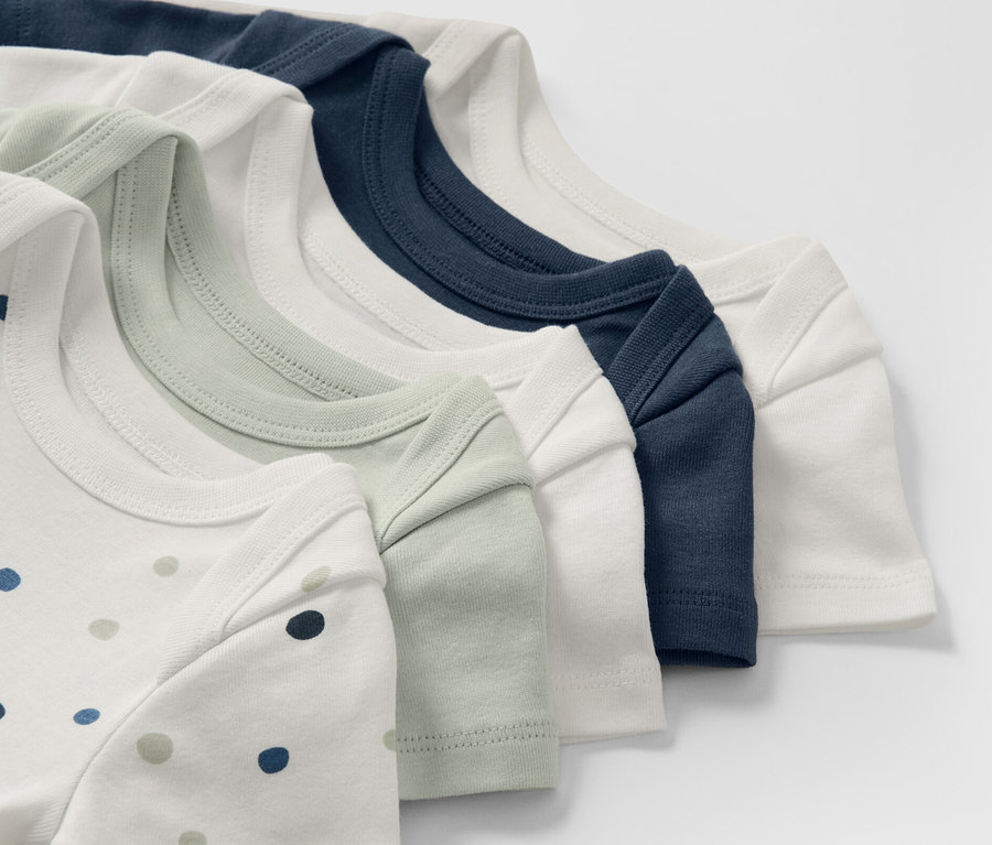 Detailaufnahme von fünf Baby-Bodys mit Mitwachsfunktion in verschiedenen Farben.