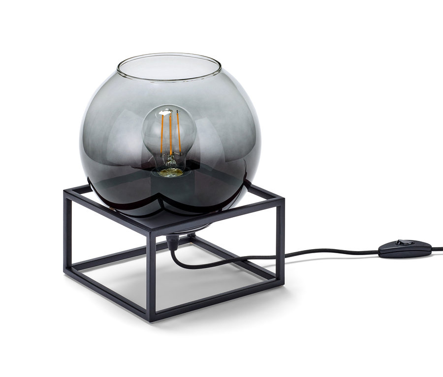 Tischleuchte mit Rauchglas-Schirm auf schwarzem Metallrahmen.