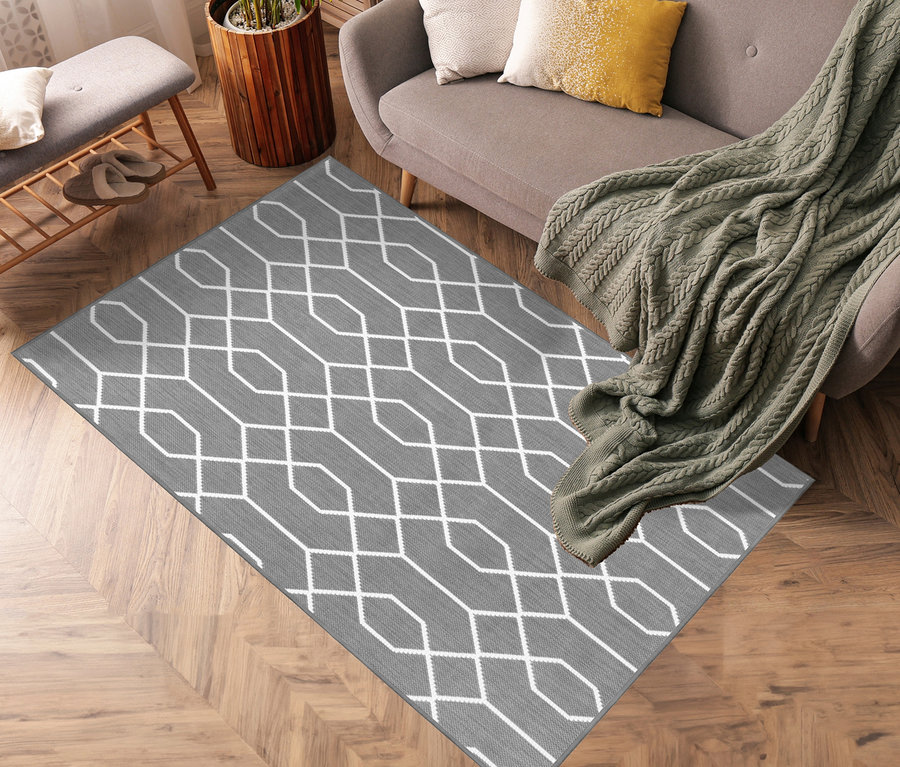 Grauer Outdoor-Wende Teppich »Geo River« mit weißem geometrischem Muster liegt im Wohnzimmer.